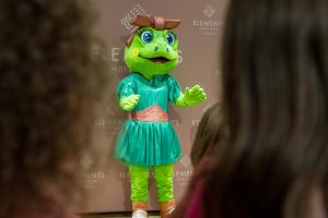 a child looking at a green mascot at Elements Hotel&Spa in Świeradów-Zdrój