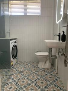 a bathroom with a toilet and a sink and a washing machine at Stylish 2BR apt, great location in Campbell