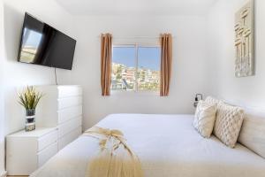 a bedroom with a bed with a tv on the wall at Arguineguín Villa Hot Tub, BBQ & Views in Patalavaca