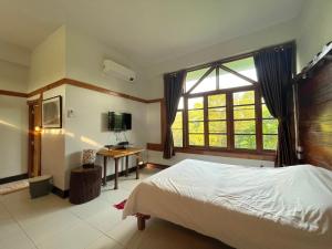 a bedroom with a bed and a desk and a window at Muangkham in Chiang Rai