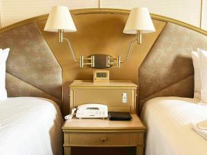 a hotel room with two beds and a phone on a night stand at Ginza Creston in Tokyo +40 photos
