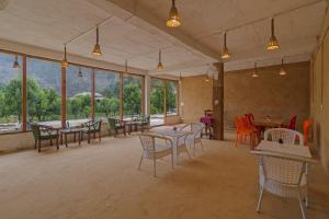 a dining room with tables and chairs and windows at Himalayan Willow in Gushaini +47 photos