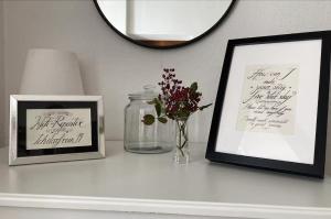 a white shelf with two pictures and a vase with flowers at Altstadtzimmer im Herzen des historischen Wiens in Vienna