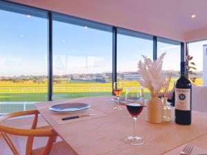 Panoramic Racecourse View - A Quiet Family Villa Over the Turf في أوكلاند: طاولة خشبية مع زجاجة من النبيذ وكأس