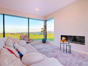 Panoramic Racecourse View - A Quiet Family Villa Over the Turf في أوكلاند: غرفة معيشة مع أريكة كبيرة ومدفأة