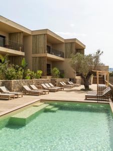 Un complejo con piscina y sillas y un edificio. en Résidence Oradoro, en Belgodère