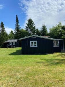 a black house in a yard with a grass field at A Cozy Older Summerhouse On A Small Island in Orø
