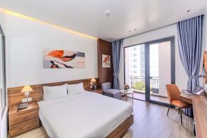 ドンホイにあるRosaLie Quảng Bình Hotelのベッドと大きな窓があるホテルの部屋