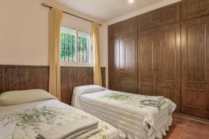 Un dormitorio con dos camas y una ventana y armarios de madera. en Casa Cantarrana, en Arriate 39 fotos más