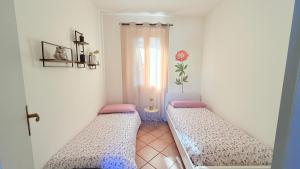 two beds in a small room with a window at L’Acero Rosso - Giardino privato e Box auto in Menaggio