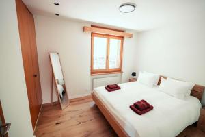 a bedroom with a white bed with two red towels on it at Stylish Lakeview Apartment Balcony & Free Parking in Laax