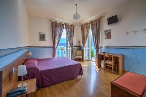 a bedroom with a purple bed and a desk and window at Hotel Riviera in Griante Cadenabbia