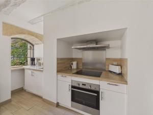 eine Küche mit weißen Schränken und einem Herd mit Backofen in der Unterkunft Maison pour 5 avec cour extérieure dans le centre in Saint-Léon-sur-Vézère + 9 Fotos