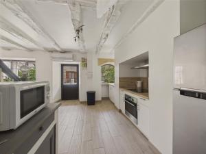 eine große Küche mit weißen Schränken und einem Fernseher in der Unterkunft Maison pour 5 avec cour extérieure dans le centre in Saint-Léon-sur-Vézère