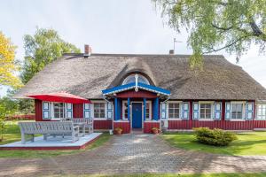 ein rot-blaues Haus mit einer Bank davor in der Unterkunft Vila Pervalka in Pervalka