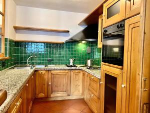 a kitchen with wooden cabinets and green tiles at Appartamento Ginepro in Livigno