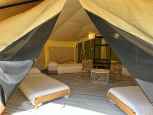 a tent with two beds and a table and chairs at Canopy Villa Glamping Park in Kampong Sum Sum