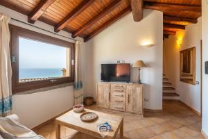 a living room with a tv and a window at Cliffside Blue in Costa Rei +24 photos