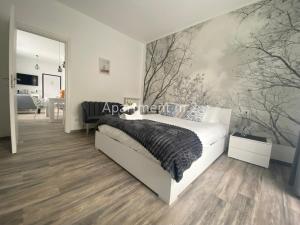 a bedroom with a white bed and trees on the wall at Il Giardino di Lilly in Porlezza