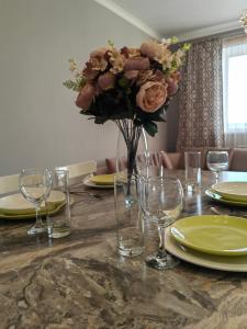 a table with a vase of flowers and glasses on it at ЖК Madina in Petropavlovsk +3 photos