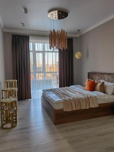 a bedroom with a large bed and a chandelier at ЖК Madina in Petropavlovsk