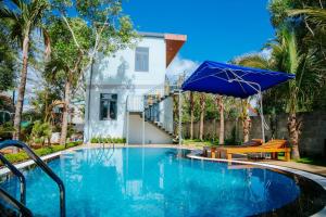 a swimming pool with a blue umbrella and a house at Quynh House-Homestay nguyên căn có hồ bơi riêng-6 phòng ngủ in Ấp Ngọc Hải +26 photos