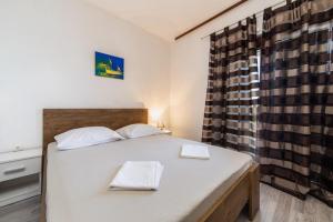 a bedroom with a large white bed and a window at Dalmata Apartments in Brist