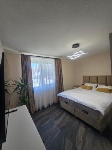 a bedroom with a bed and a large window at CityVibe Apartament in Luduş