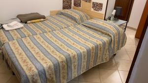 a large bed with a blue and yellow striped comforter at Alloggio Turistico Grottaferrata in Grottaferrata