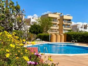 a swimming pool with flowers in front of a building at Winahost Apartamentro Cunit Vistas al Mar in Cunit