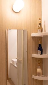 Un baño con espejo y estantes con botellas. en 北宿kitayado, en Osaka