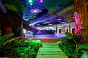 a room with a tree and a stage with plants at Vakantiepark BreeBronne in Maasbree +14 photos