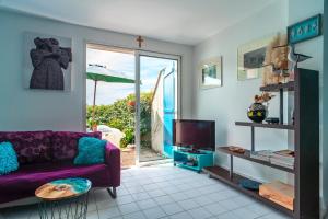 Una sala de estar con un sofá morado y un televisor. en Locmariaquer Mer & Plage - à 50m de la plage, en Locmariaquer