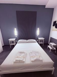 una camera da letto con un grande letto bianco con due tavoli di La cittadella rooms 2 a Cagliari