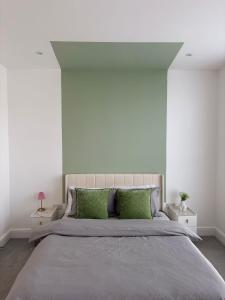 una camera da letto con un letto grande con cuscini verdi di Stunning 3 Bed Apartment with Seaview a Worthing