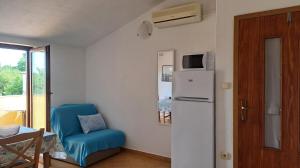 a small room with a refrigerator and a blue chair at Apartment Krizanovic in Malinska