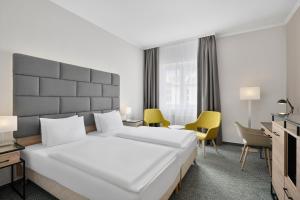 杰尔Danubius Hotel Raba的酒店房间里有一张白色的大床和椅子