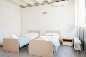 two twin beds in a room with white walls at Appartamenti tra Lago e Montagna CASA IDEALE LECCO in Lecco
