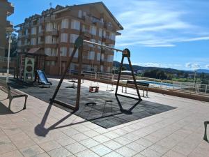 a park with two swings in front of a building at R2R - Apartamento en Noja 2 dormitorios - C18A02 in Noja