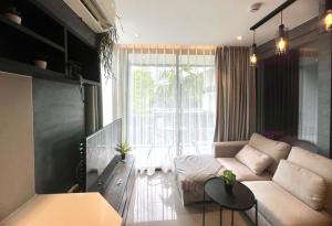 a living room with a couch and a large window at Deluxe apartment Citygate Condo by Lofty in Kamala Beach