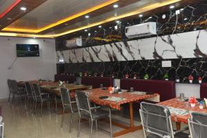 a dining room with tables and chairs and a tv at Hotel Atithi Grand, Gobarsahi in Muzaffarpur