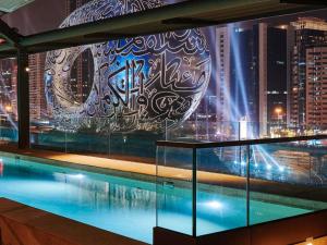 a swimming pool with a view of a city at night at 25hours Hotel Dubai One Central in Dubai