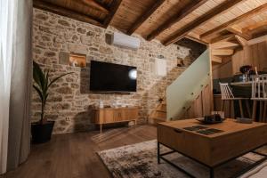 a living room with a tv on a stone wall at Orion Homes & Villas in Choudetsi