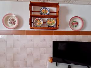 a flat screen tv sitting on a wall with plates at Casa da Bia in Nisa