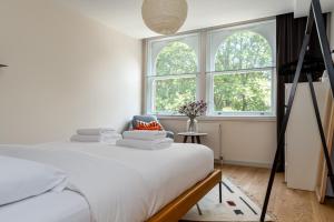 a white bedroom with a bed and two windows at 2 bedroom apartment in London Bridge in London