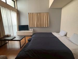 a bedroom with a bed and a table and a television at エスポアール新町102 in Kumamoto