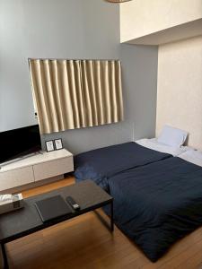 a bedroom with a bed and a table and a television at エスポアール新町102 in Kumamoto +7 photos