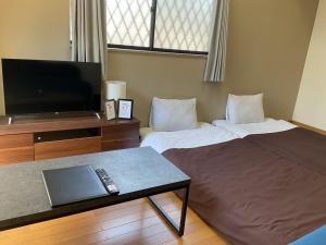 a hotel room with two beds and a television at エスポアール新町103 in Kumamoto