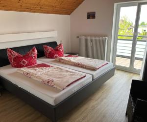 two beds in a bedroom with red pillows on them at Ferienwohnung Stefanie in Hagnau
