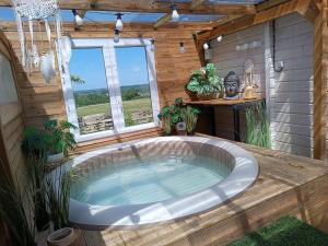 a large bath tub in a room with a window at La Belle brune, avec jacuzzi in Alincthun